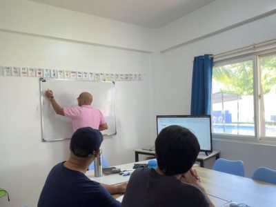 A teacher standing in front of a classroom, teaching a business course